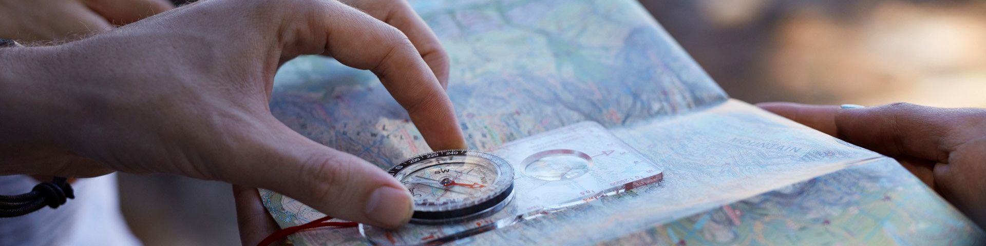 Hands, holding a compass over a map